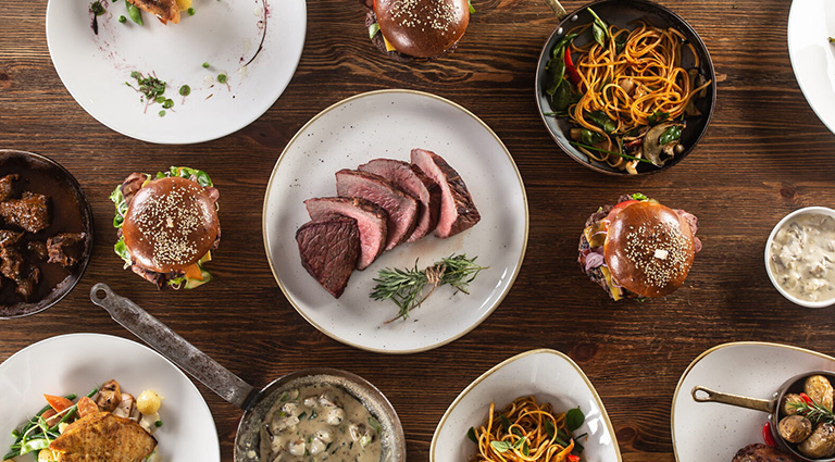 Gedeckter Tisch von Oben. Teller mit verschiedenen Gerichten. Fleisch und Pflanzliche.