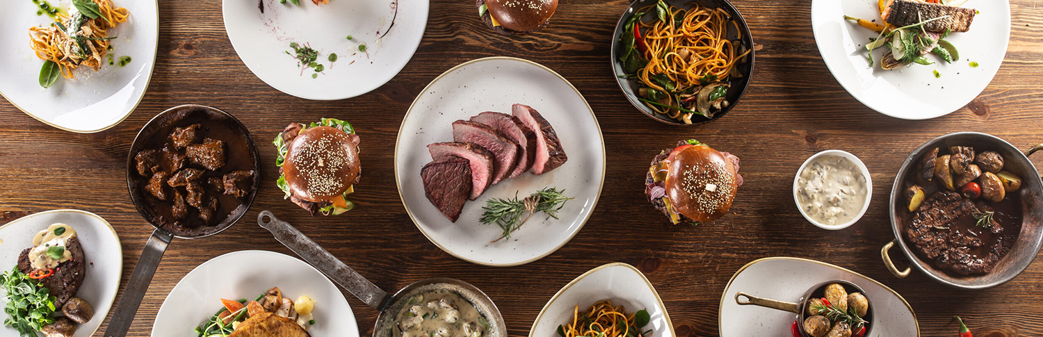 Gedeckter Tisch von Oben. Teller mit verschiedenen Gerichten. Fleisch und Pflanzliche.